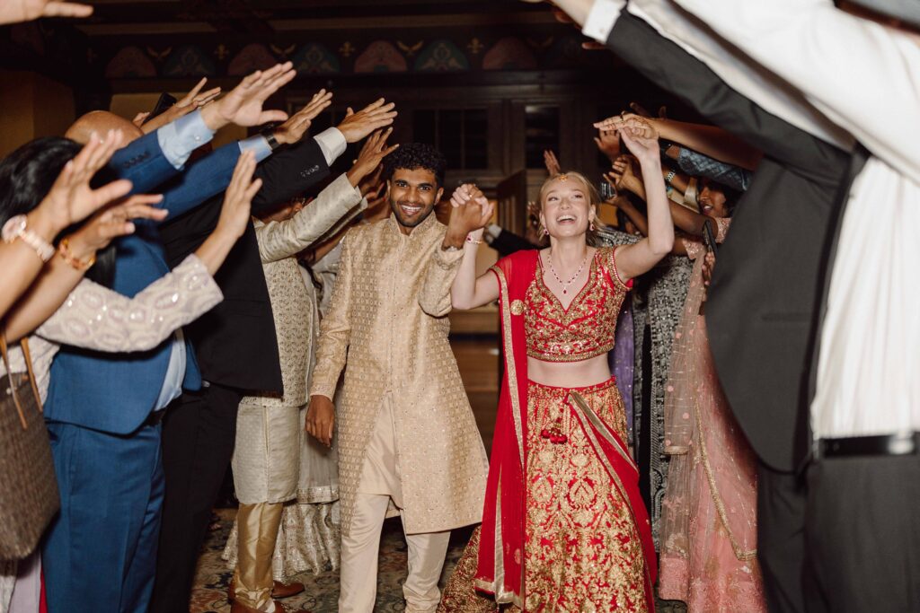 bride and groom exiting Hotel Syracuse wedding Grand ballroom in Indian attire